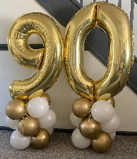 Gold and white balloons forming the number '90' on a plain background